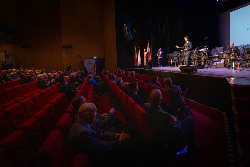 Defensieminister Ruben Brekelmans spreekt vanaf een podium het publiek toe.