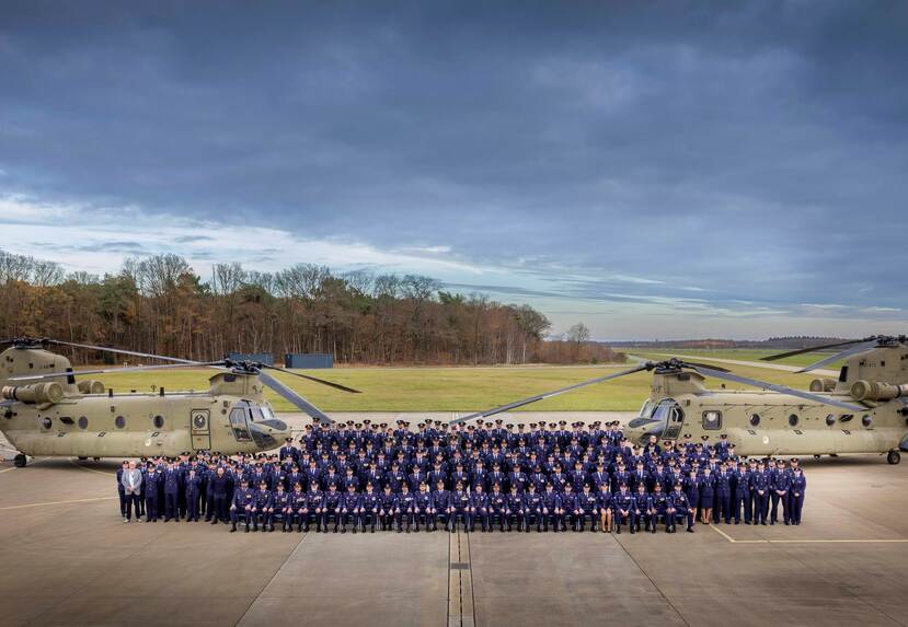 Groepsfoto met personeel van 298 Squadron voor twee Chinooks buiten op het platform.
