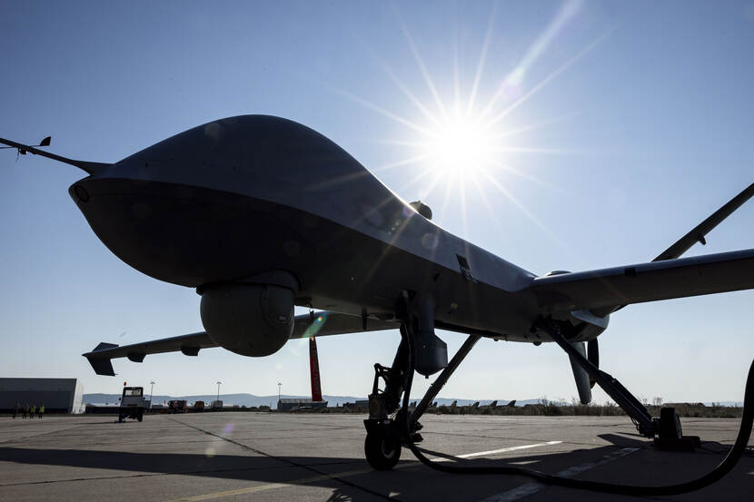 Silhouet van een MQ-9 op een platform tegen een felle zon.