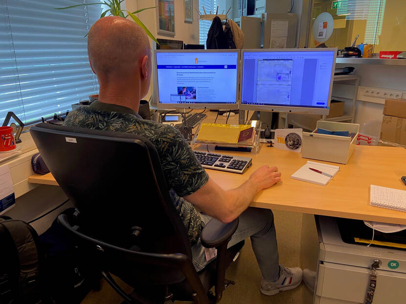 Bart van de ID-desk op de rug gefotografeerd, terwijl hij achter zijn computer werkt.