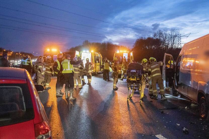 Groep hulpverleners met daarachter twee ambulances.