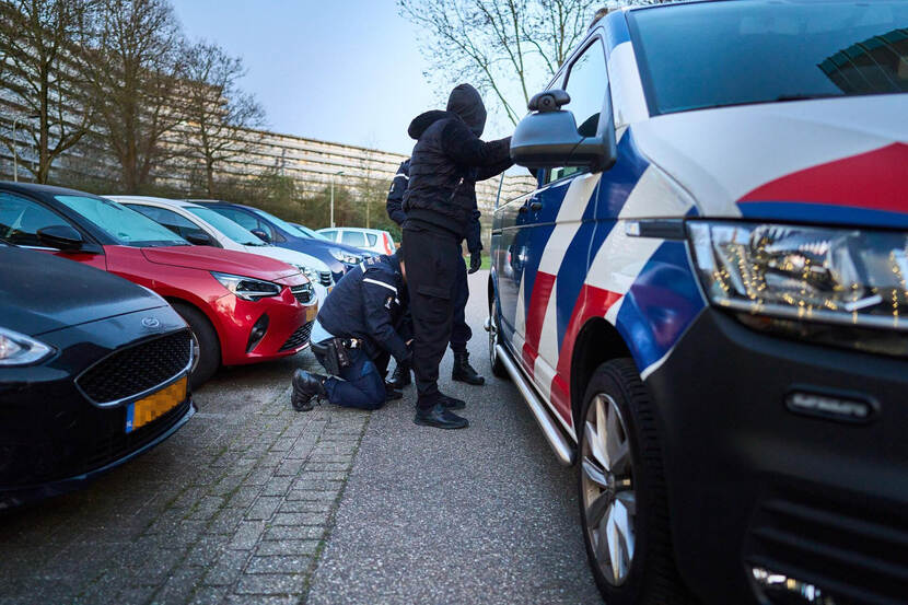 Marechaussees fouilleren een verdachte die met gespreide armen en benen tegen een busje staat.