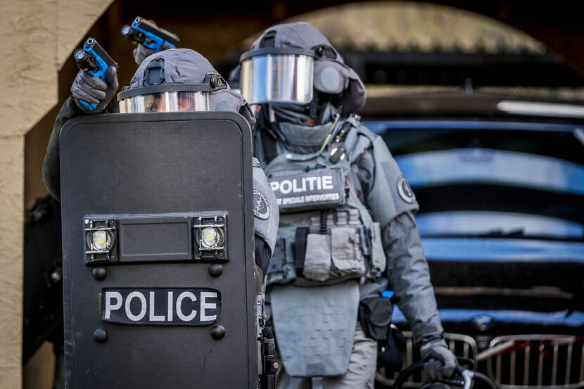 Leden van een AT brengen vanachter hun ballistische schild pistoolvuur uit.