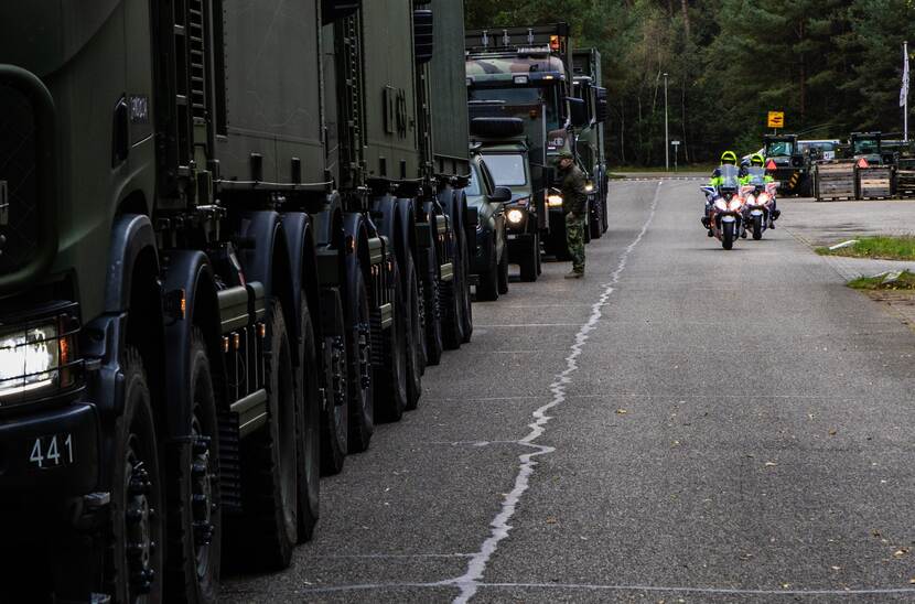 Marechaussee te motor begeleiden legervoertuigen