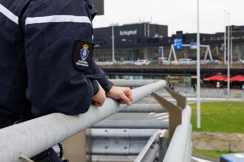 Handen van een marechaussee op reling.