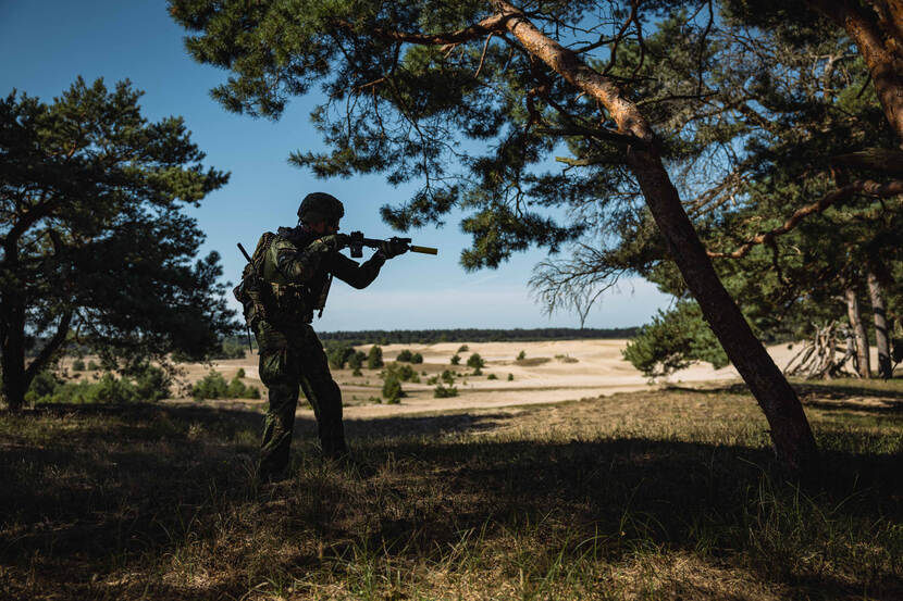 Marechaussee op de hei richt lang wapen.