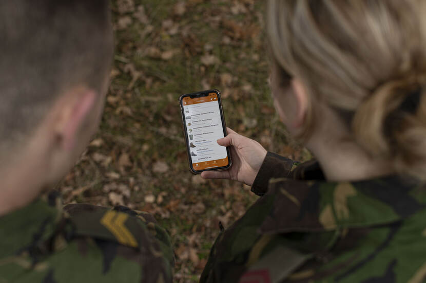 Twee militairen bekijken een smartphone met de KPU-app.