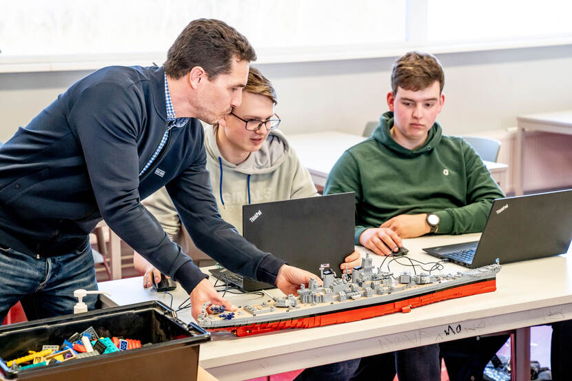 Projectleider Michael van Alderwegen (links) met leerlingen bij een Lego-scheepsmodel
