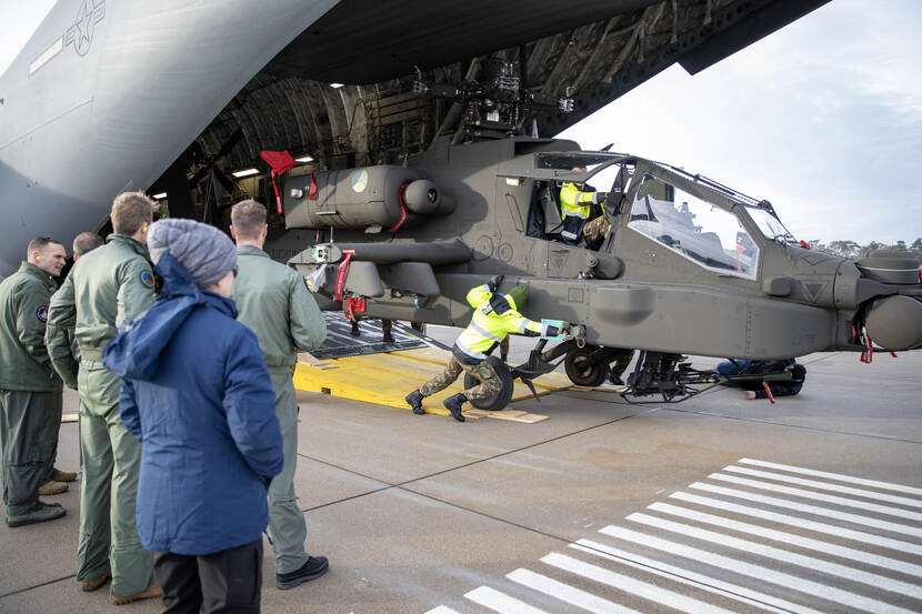 Grondpersoneel duwt een Apache van de ramp van een C-17-transportvliegtuig.