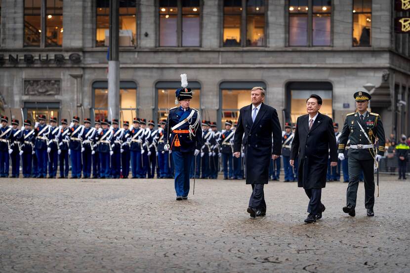 Koning Willem-Alexander en de Zuid-Koreaanse president Yoon Suk Yeol op de Dam in Amsterdam met een hoge Koreaanse officier en de paradecommandant van de Koninklijke Marechaussee. Op de achtergrond een detachement marechaussees.