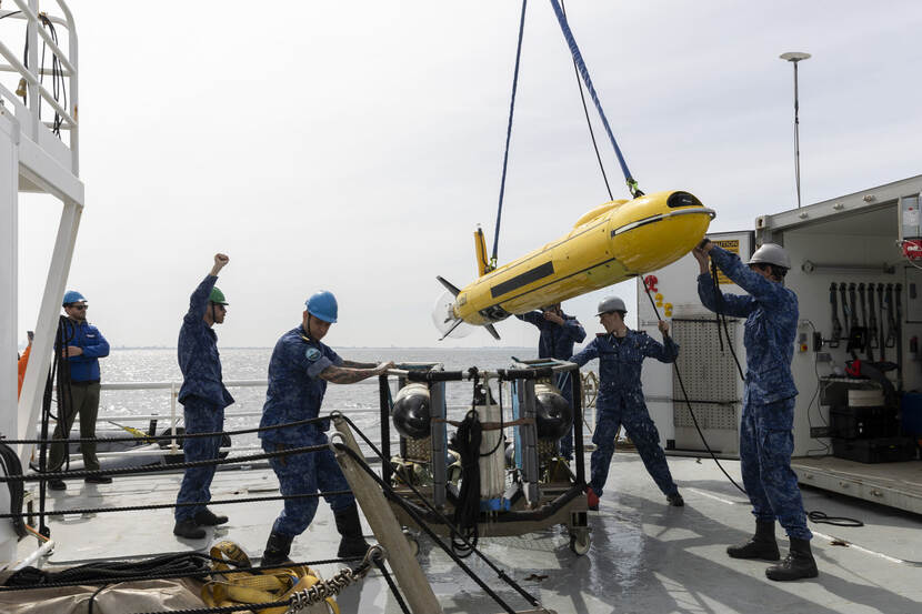 Militairen hijsen een onderwaterdrone op, op een schip