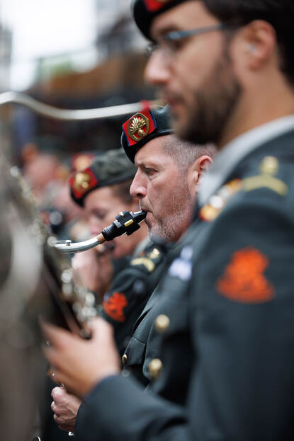 Lid van het militair orkest blaast op een saxofoon.