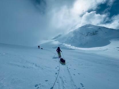 Bergbeklimmer met een slee achter zich aan baant zich een weg over de besneeuwde berg.