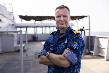 Commandeur George Pastoor in marine-uniform op het dek van Zr.Ms. Karel Doorman.