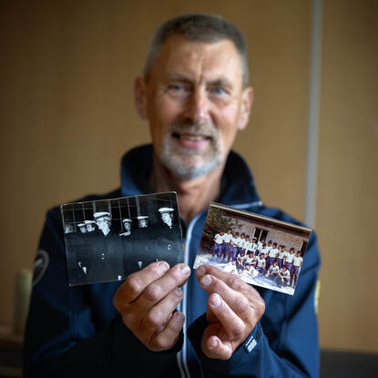 Ton Stavenuiter houdt voor zijn gezicht enkele foto’s van vroeger.