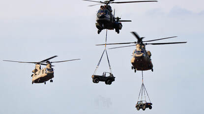 Links vier F-35 in de lucht, rechts drie Chinooks, waarvan twee met een jeep als underslung.