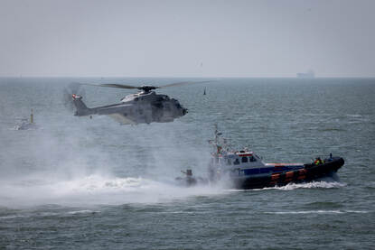 Een Belgische NH90 maritieme helikopter voert in samenwerking met een oranje