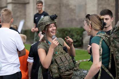 Militairen dalen met een touw af van de kerk, rechts twee lachende vrouwen die veel plezier beleven aan het evenement.