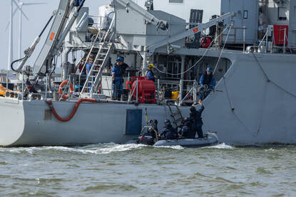 Duikers komen weer aan boord van BNS Lobelia, terwijl een politiebootje terugkeert naar de Eemshaven.