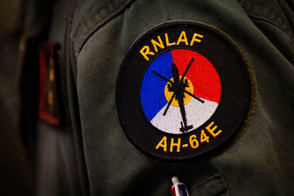 Viermaal een mouw van een militair uniform met daarop de vlaggen en logo’s van respectievelijk Nederland, de Verenigde Staten, het Verenigd Koninkrijk en Polen.