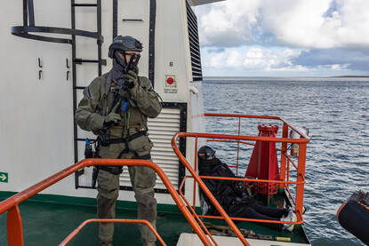 Een operator staat met zijn geweer gereed op een scheepsdek
