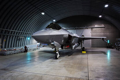 Een F-35 in een shelter en een F-35 wordt de shelter uitgereden.