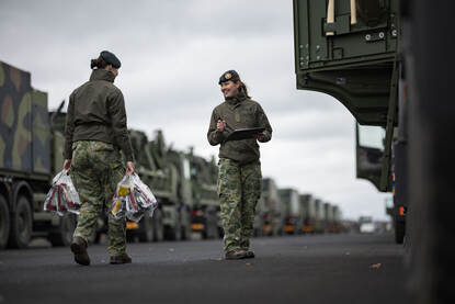 Twee foto’s waarop militairen bezig zijn met beladen van de colonne met legervrachtwagens.