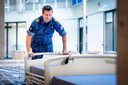 Links duwt een marineman een ziekenhuisbed. Rechts laden mensen ziekenhuisbedden uit een vrachtwagen.