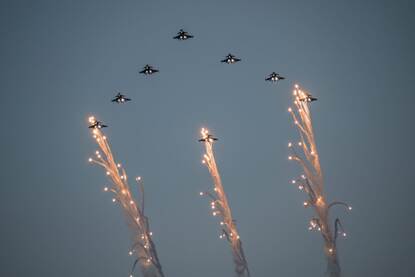 8 straaljager vliegen in formatie met daaronder 3 kerstbomen.