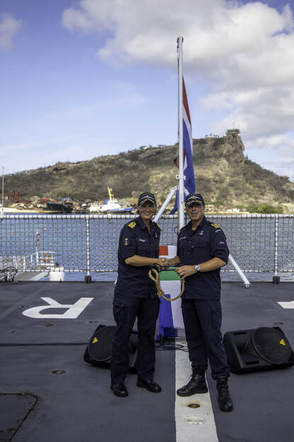2 marinemensen geven elkaar de hand, op het dek van een marineschip.