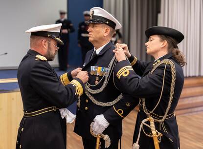 Admiraal Tas en zijn adjudant brengen bij adjudant Heeringa het nestel aan op zijn uniform.