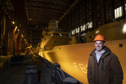 Cees van Rijn in het dok, de werkplaats van de DMI, met op de achtergrond een schip dat in onderhoud ligt.