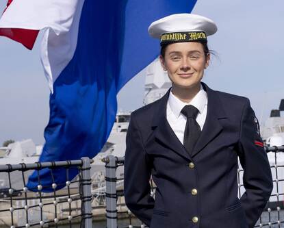 Militair poseert voor Nederlandse vlag.