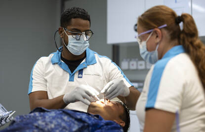 Portretfoto van tandarts Dwight die een patiënt in z’n stoel onderzoekt.