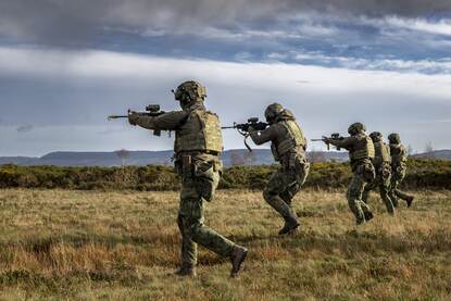 Mariniers lopen schietend voorwaarts en mariniers lopen in de mist door het bos.