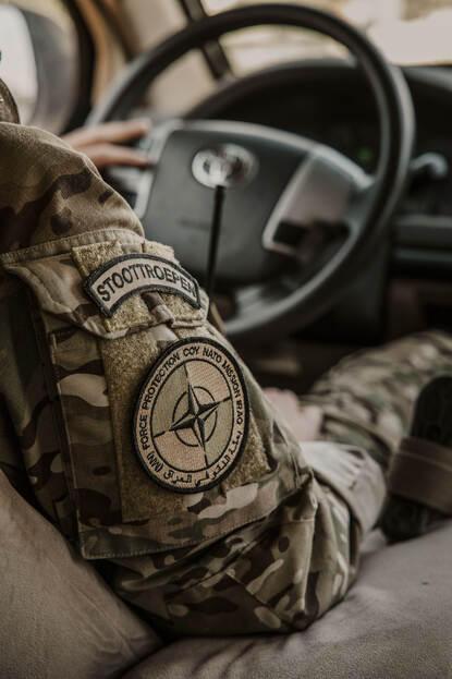Patch op arm met tekst Stoottroepen en daaronder ronde patch met Multinational Force Protection Company NATO Mission Iraq.