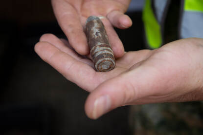 Close-up beeld van een mini-granaat in de hand, waarbij hij wijst naar de geleideband, die nog volledig intact is.