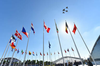 Vlaggen voor het NAVO-hoofdkwartier met vier vliegtuigen in de lucht.