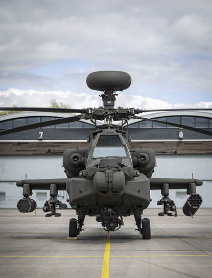 Vooraanzicht van een AH-64E met bovenop de rotor de fire control radar.