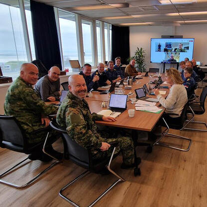 PC-LSK Adang aan een tafel met marinemilitairen.