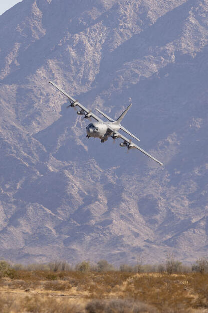 Een C-130 maakt een scherpe bocht om te landen, met een berg op de achtergrond.