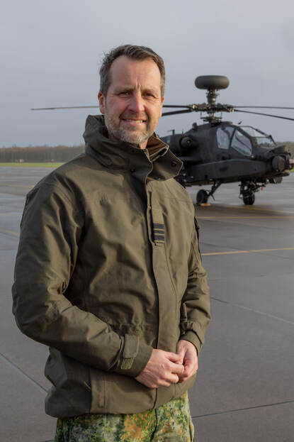 Majoor Marc de Vroome poseert buiten voor een Apache.