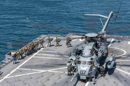 Een MH-53 staat op het achterdek van de Johan de Witt en mariniers lopen er in een slinger uit.
