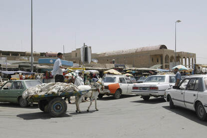 Links: auto’s en een ezelkar op straat in een Iraakse stad. Rechts: Vier mannen naast elkaar bij het doorknippen van een oranje lint.
