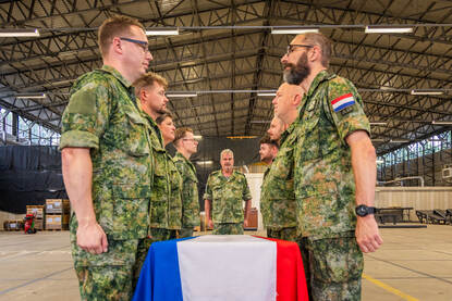 De acht militairen aan weerszijden van de kist vouwen de Nederlandse vlag tot een strak pakketje.