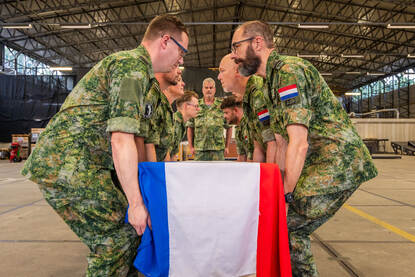 De acht militairen aan weerszijden van de kist vouwen de Nederlandse vlag tot een strak pakketje.
