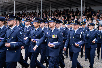 Officieren van de luchtmacht marcheren met de bul onder hun arm.