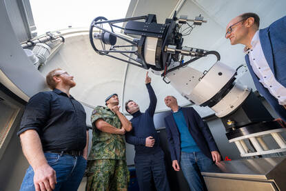 Majoor Scott met vier wetenschappers staand in de koepel van de tracking sensor.