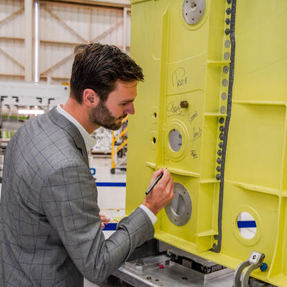 Thijs zet zijn naam op een grote gele stalen balk.