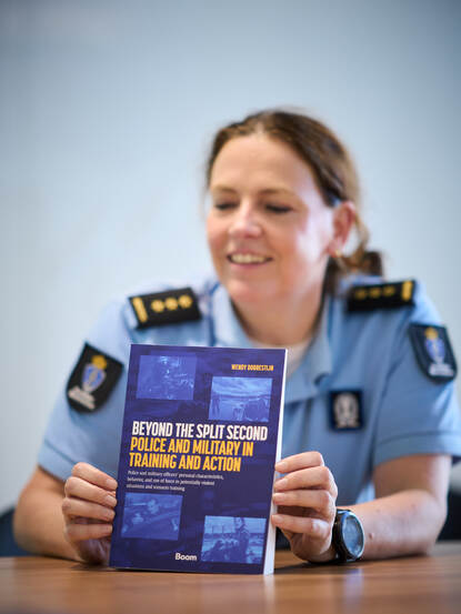 Kolonel dr. Dorrestijn houdt haar boek vast. Daarop staat de titel ‘Beyond the Split Second - Police and Military in Training and Action’.